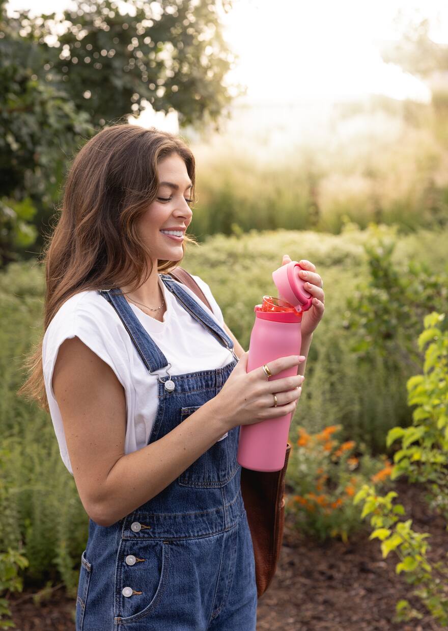 Woman opening a pink insulated water bottle